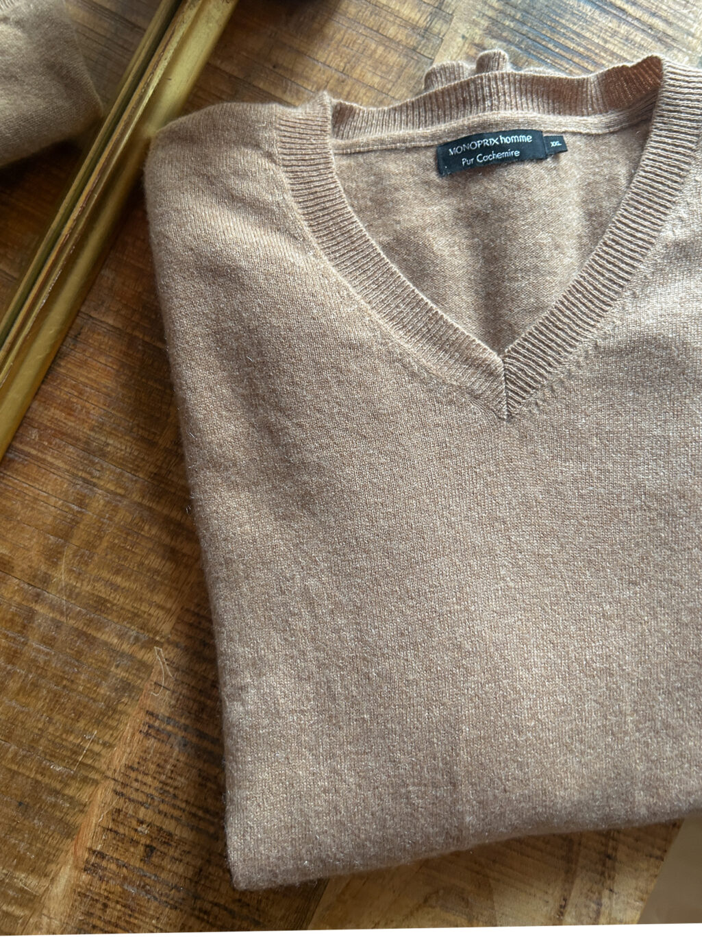 Monoprix Cashmere Pullover in Beige mit V-Neck, gefaltet auf Holztisch.
