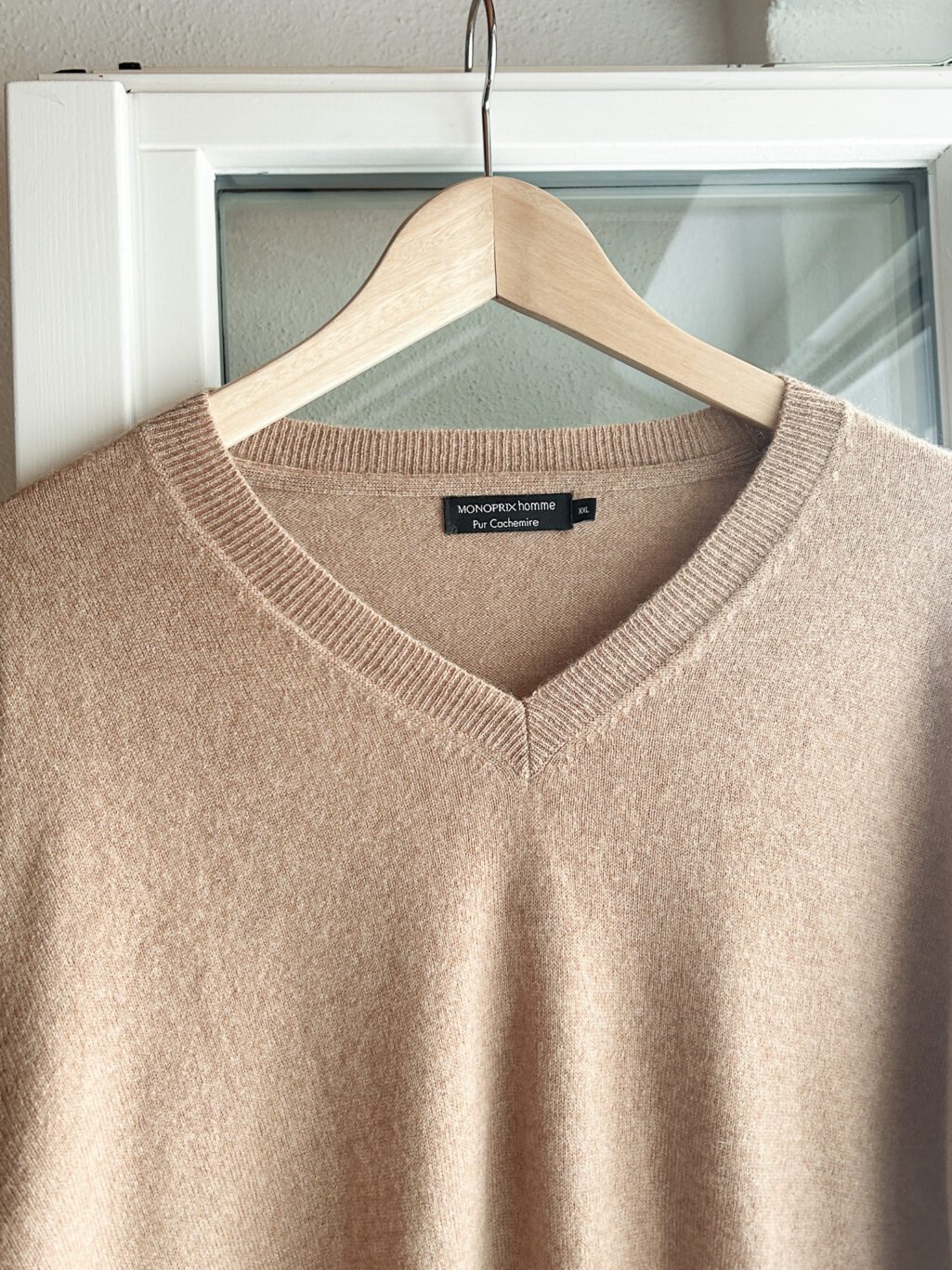 Monoprix Cashmere Pullover in Beige mit V-Neck, aufgeh&auml;ngt an Holzb&uuml;gel.