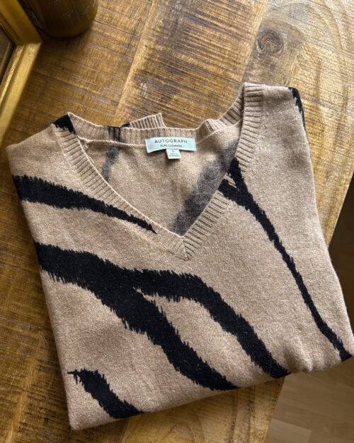 Cashmere Pullover von Autograph mit V-Neck in Beige / Braun mit Animal Print. Secondhand gefaltet auf Holztisch.