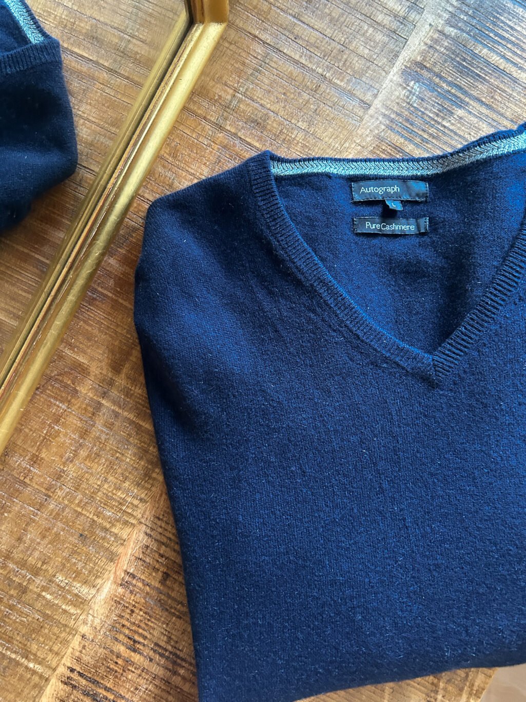 Blauer Autograph Cashmere Pullover mit V-Neck f&uuml;r Herren. Gefaltet auf Holztisch.