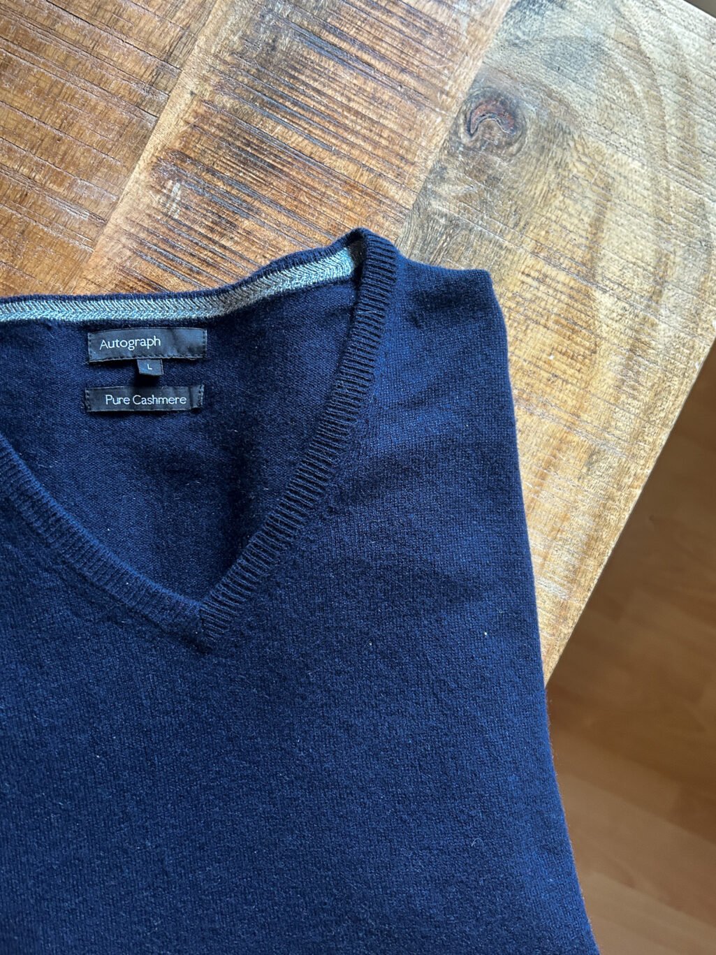 Blauer Autograph Cashmere Pullover mit V-Neck f&uuml;r Herren. Gefaltet auf Holztisch.
