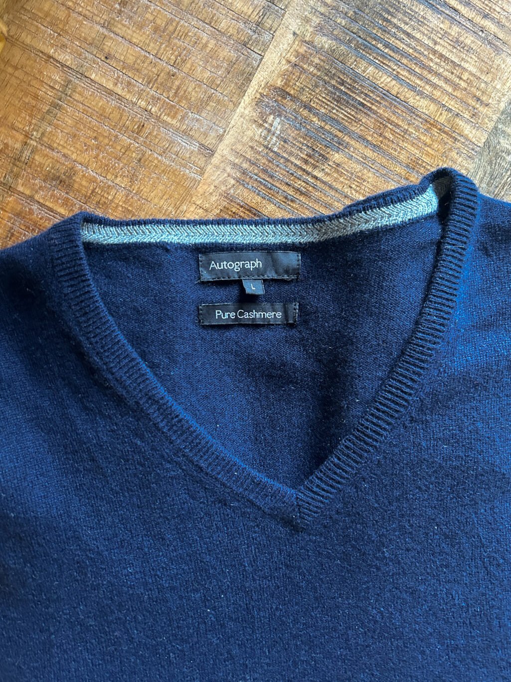 Blauer Autograph Cashmere Pullover mit V-Neck f&uuml;r Herren. Gefaltet auf Holztisch.