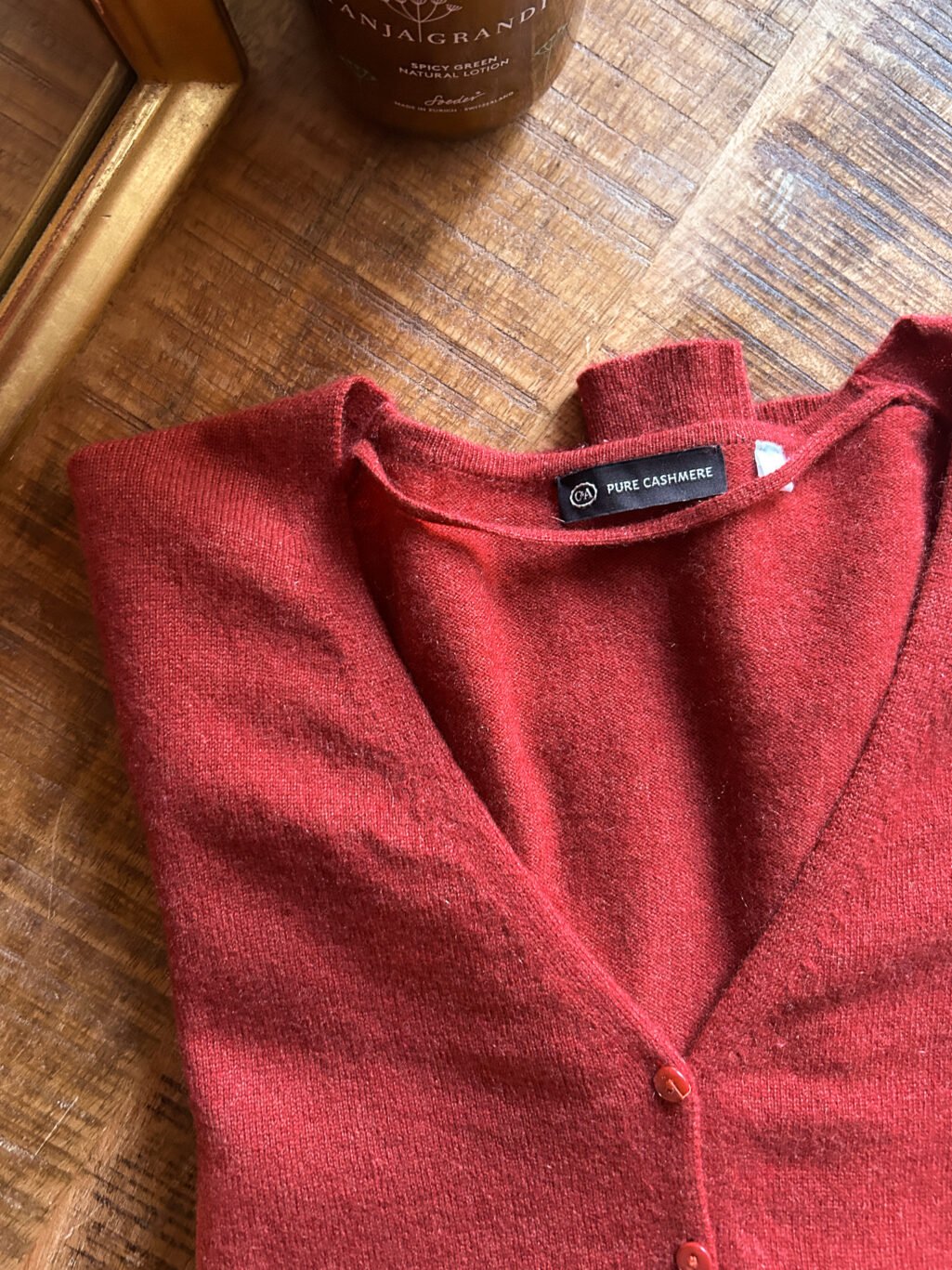 C&A Cashmere Cardigan in Orange Rot mit Kn&ouml;pfen. Preloved. Gefaltet auf Holztisch.