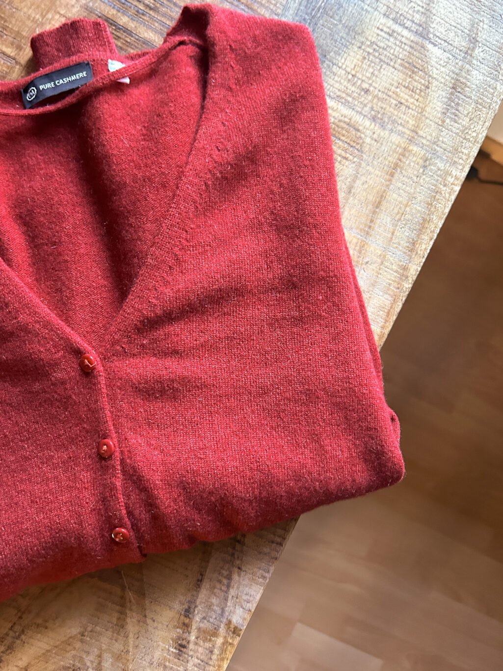 C&A Cashmere Cardigan in Orange Rot mit Kn&ouml;pfen. Preloved. Gefaltet auf Holztisch.
