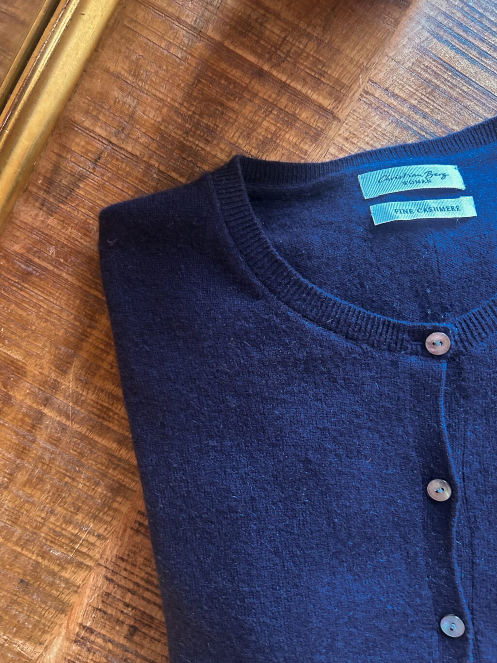 Christian Berg Cardigan aus 100% Kaschmir in Dunkelblau. Secondhand. Gefaltet auf Holztisch.