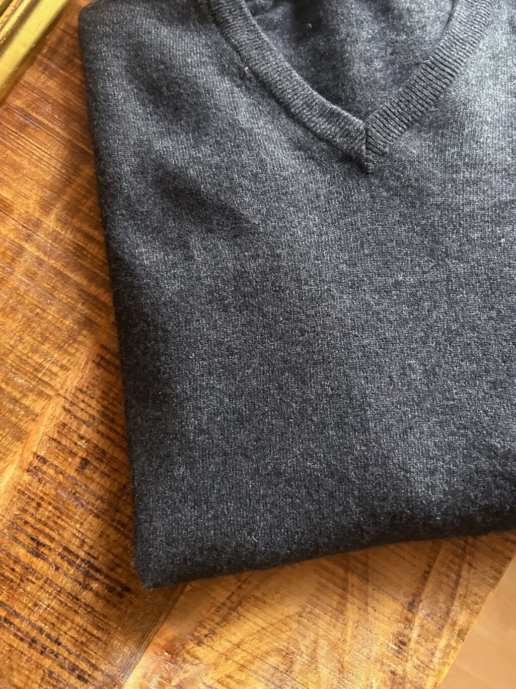Dunkelgrauer preloved Cashmere-Pullover von Livergy mit V-Ausschnitt, gefaltet auf Holztisch, feiner Strick aus 100 % Cashmere.