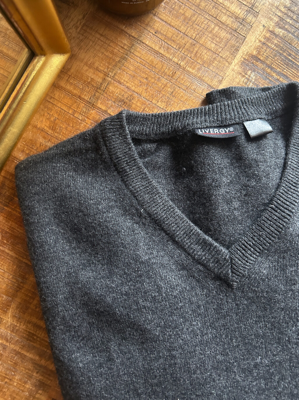 Dunkelgrauer preloved Cashmere-Pullover von Livergy mit V-Ausschnitt, gefaltet auf Holztisch, feiner Strick aus 100 % Cashmere.