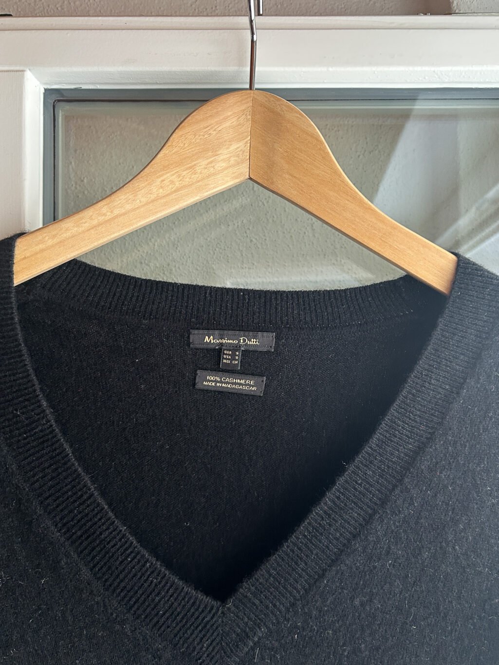 Secondhand Cashmere Pullover von Massimo Dutti in Schwarz mit V-Neck, aufgeh&auml;ngt an Kleiderb&uuml;gel.