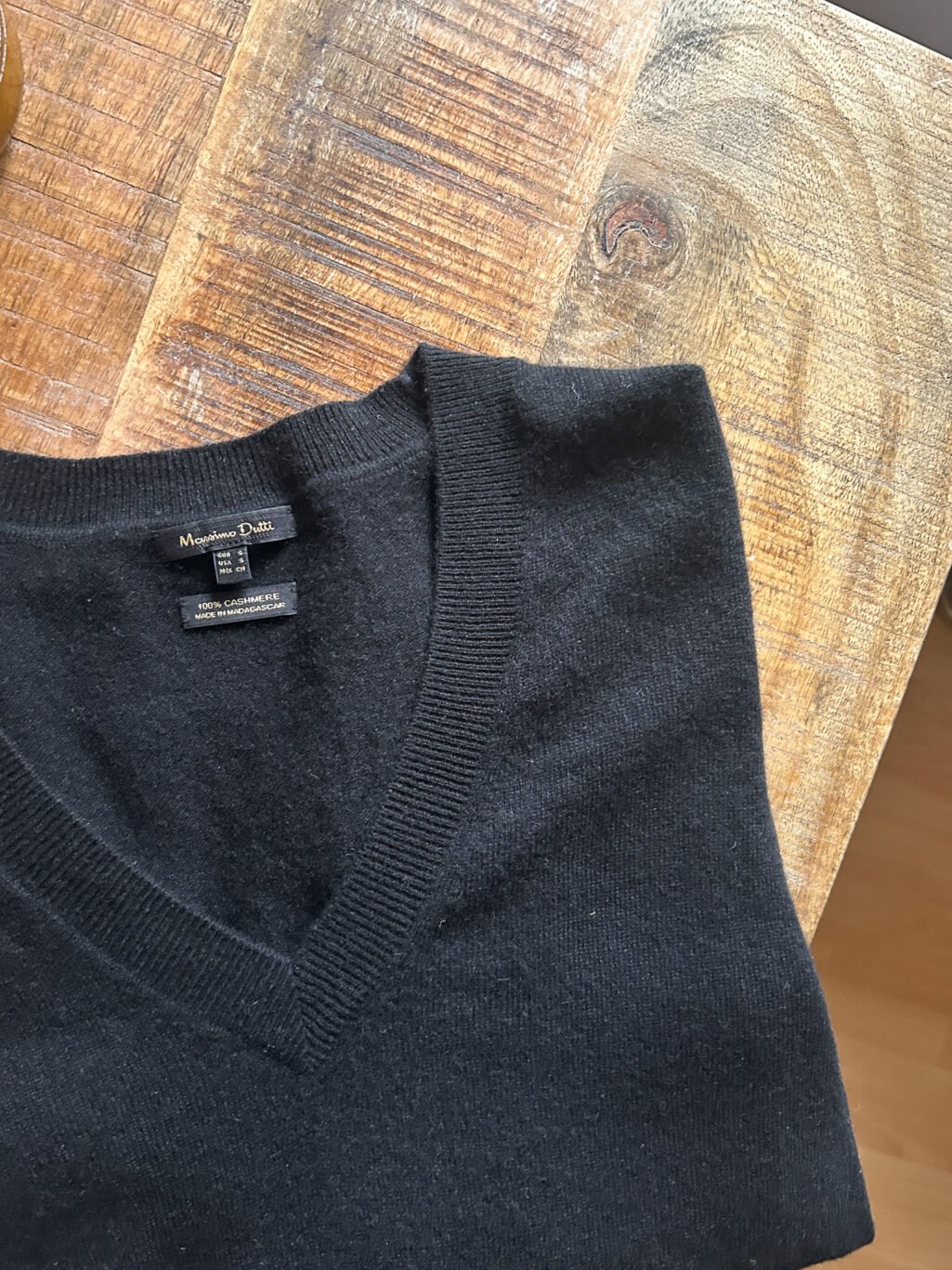 Secondhand Cashmere Pullover von Massimo Dutti in Schwarz mit V-Neck, gefaltet auf Holztisch.