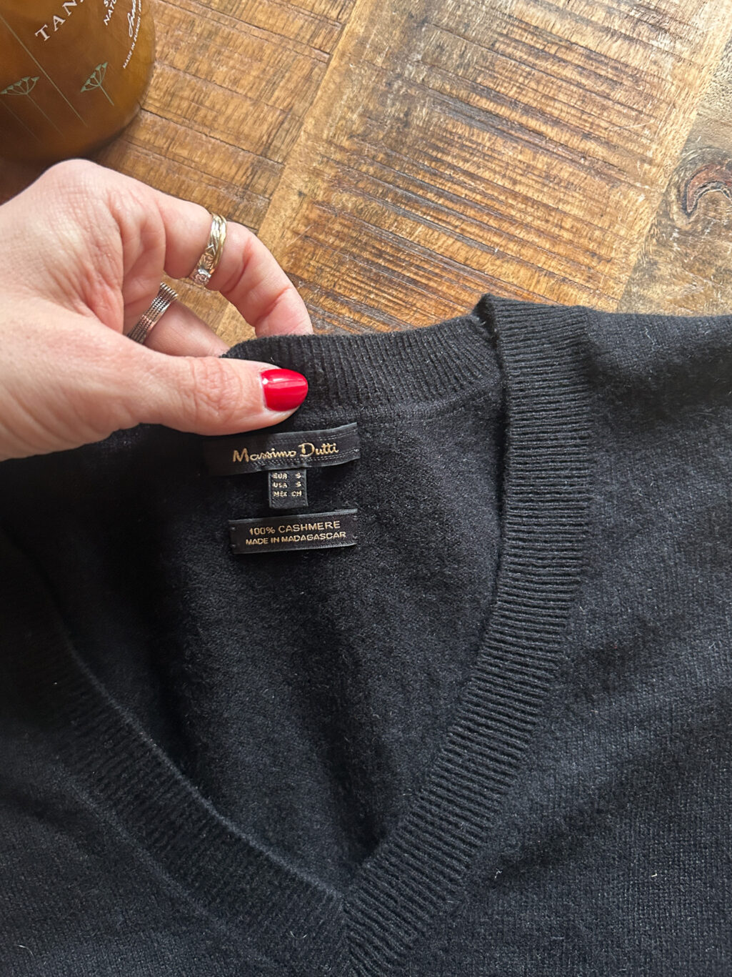 Secondhand Cashmere Pullover von Massimo Dutti in Schwarz mit V-Neck, gefaltet auf Holztisch.