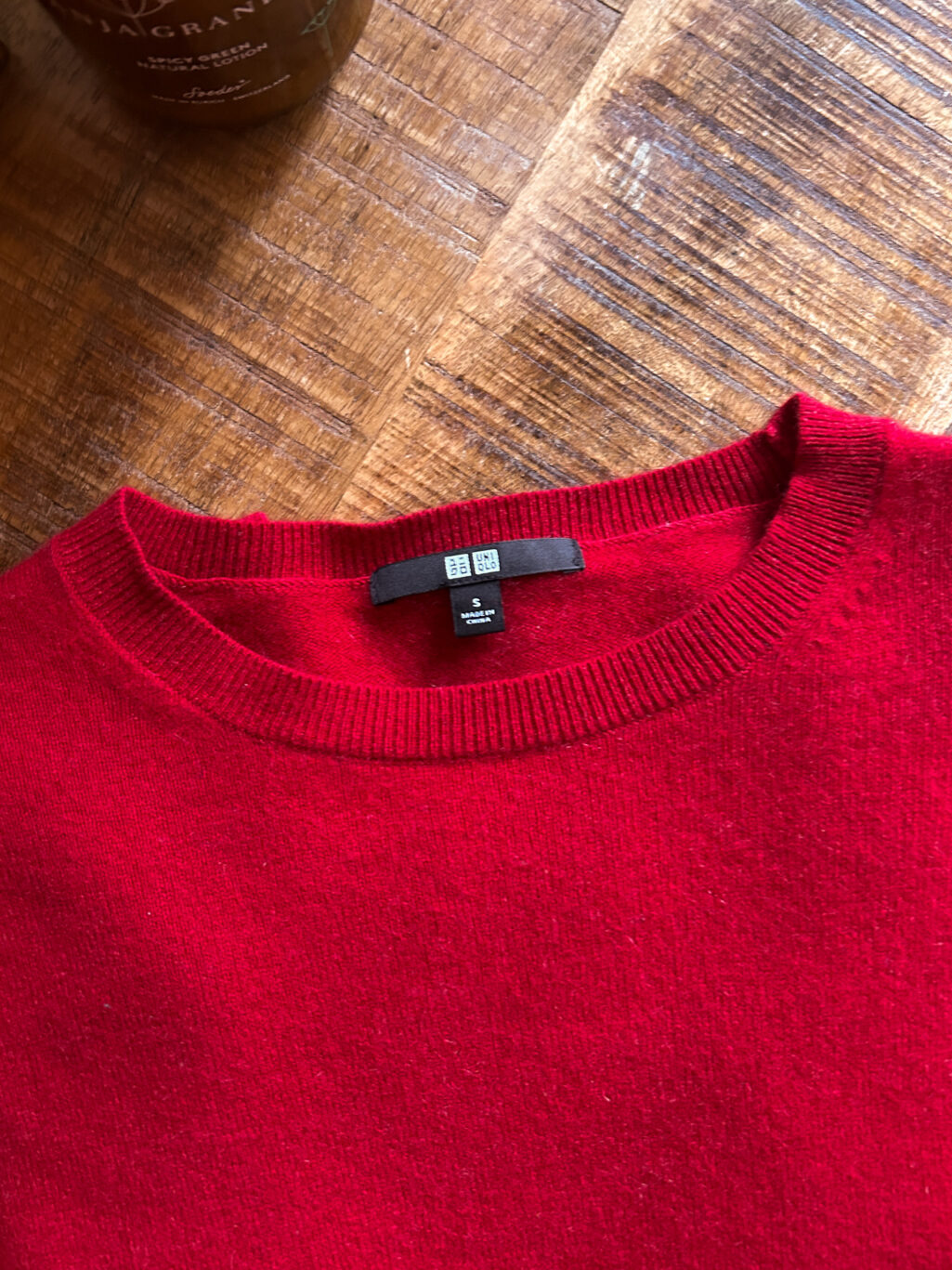 Secondhand Kaschmirpullover von Uniqlo in Rot. Gefaltet auf Holztisch.