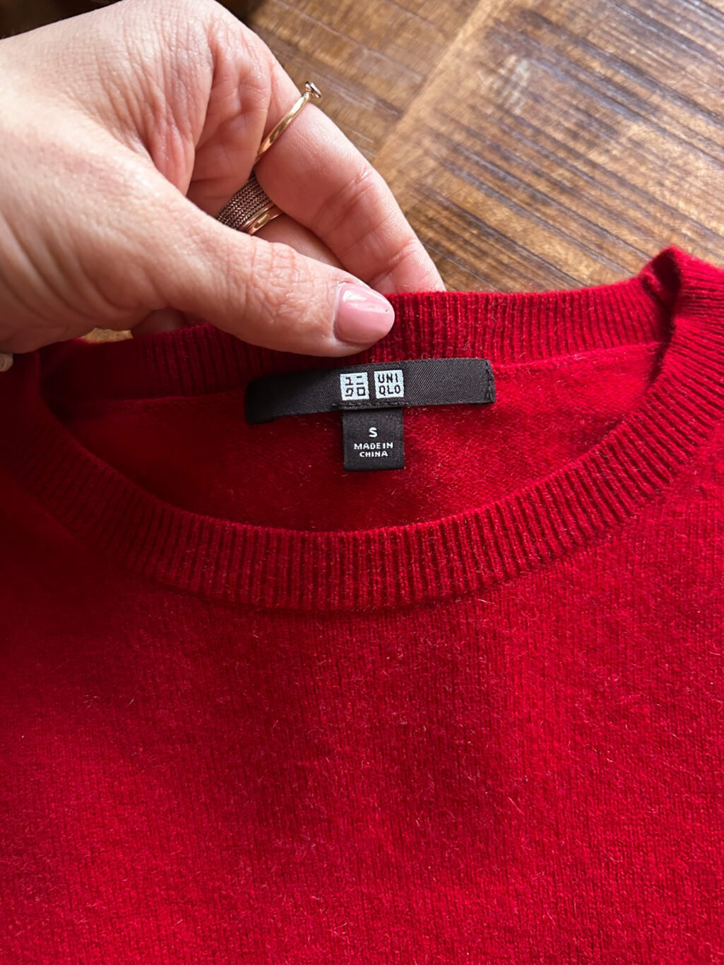 Secondhand Kaschmirpullover von Uniqlo in Rot. Gefaltet auf Holztisch.