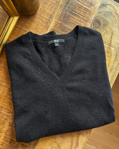 Cashmere Pullover von Uniqlo mit V-Neck Schwarz. Secondhand gefaltet auf Holztisch.
