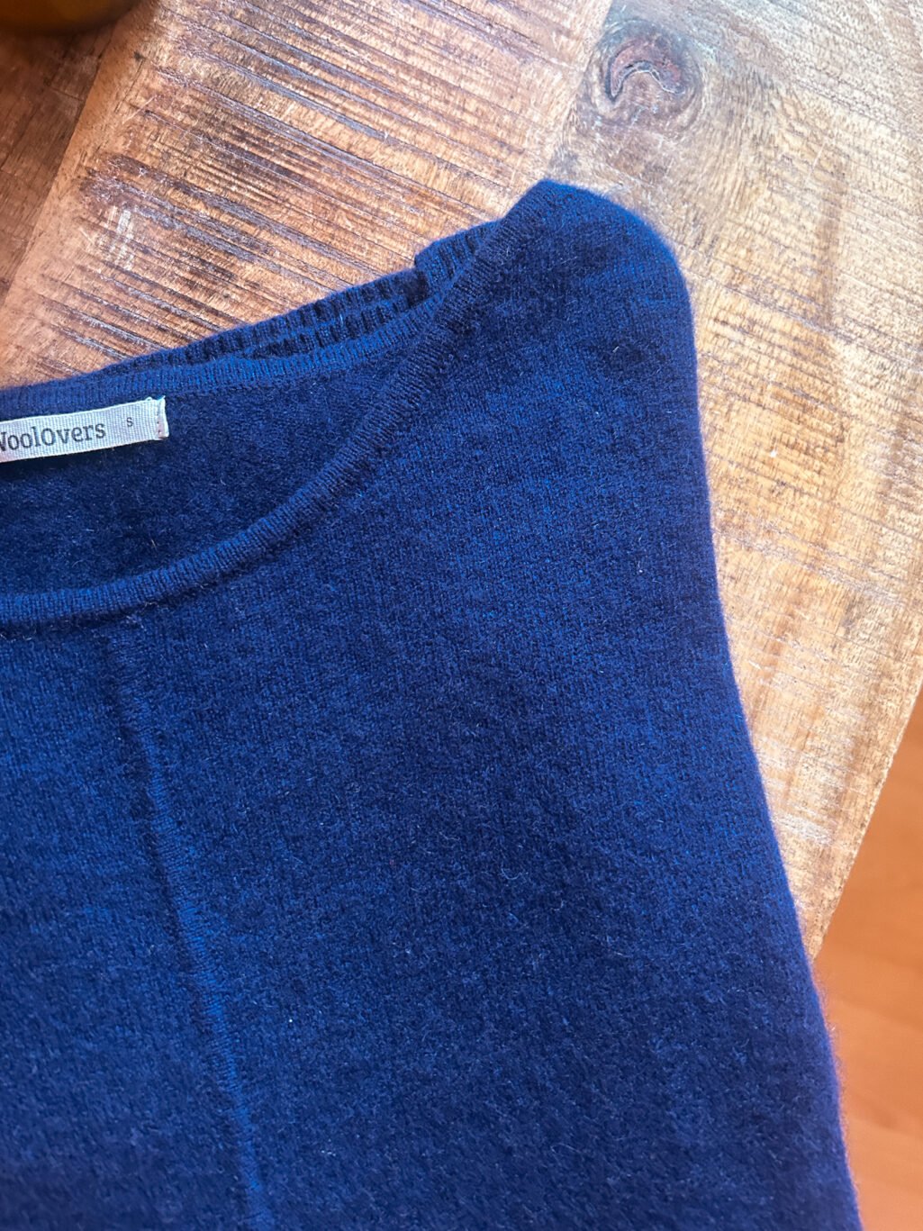 WollOvers 100% Cashmere Pullover in Blau, gefaltet auf Holztisch. Secondhand.