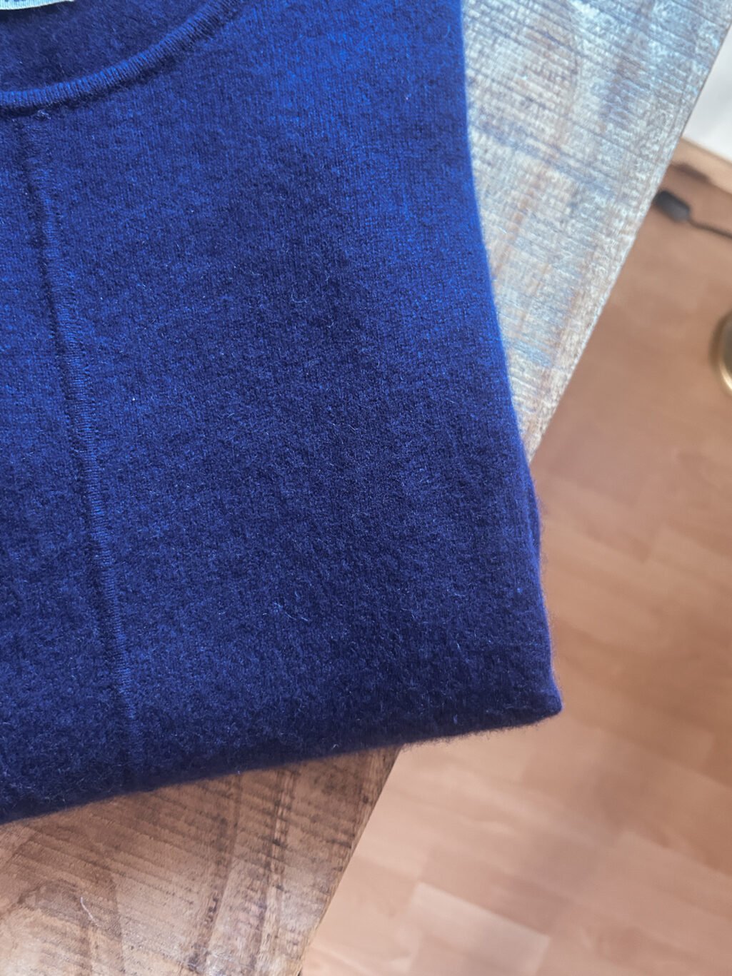WollOvers 100% Cashmere Pullover in Blau, gefaltet auf Holztisch. Secondhand.