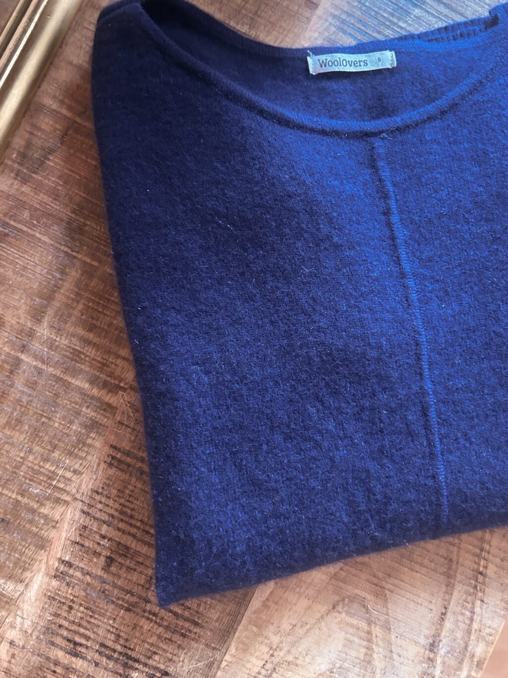 WollOvers 100% Cashmere Pullover in Blau, gefaltet auf Holztisch. Secondhand.
