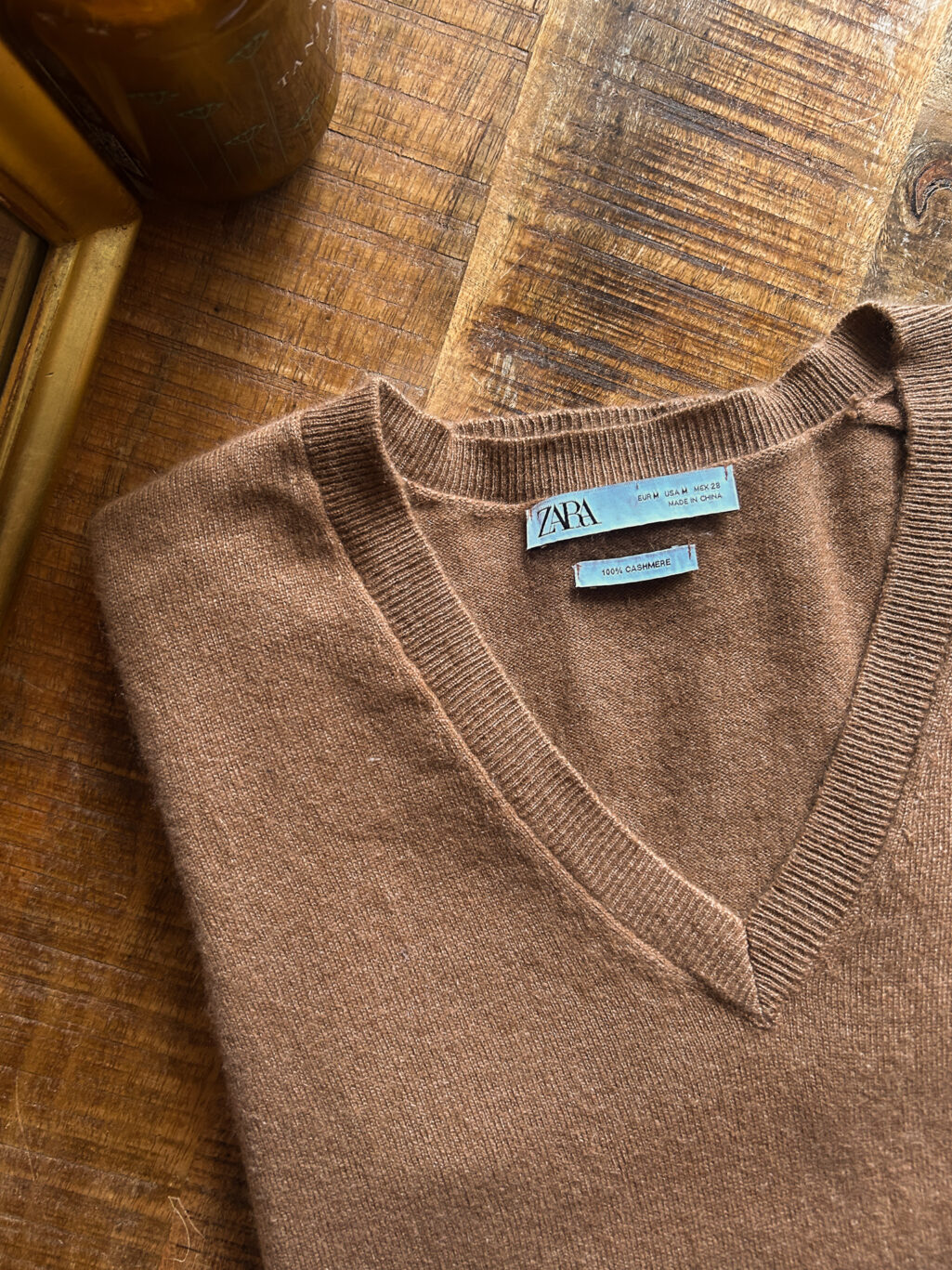 Zara brauner preloved Cashmere Pullover mit V-Neck, gefaltet auf Holztisch.