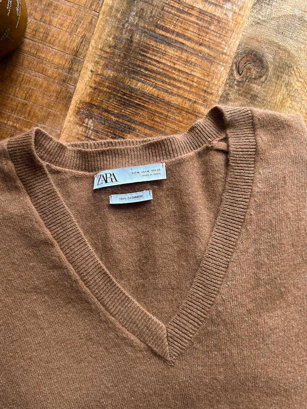 Zara brauner preloved Cashmere Pullover mit V-Neck, gefaltet auf Holztisch.