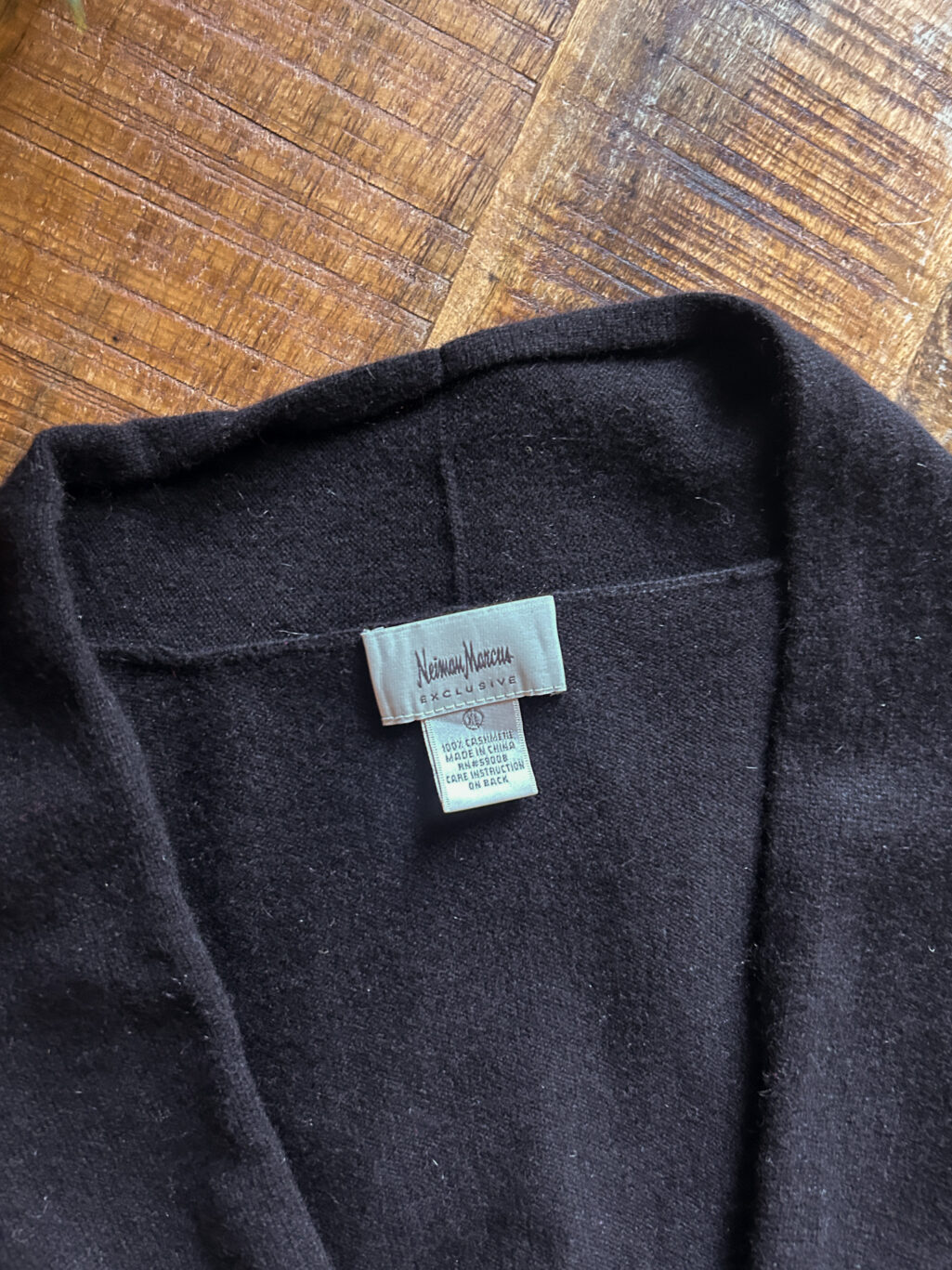 Schwarzer preloved Cashmere Cardigan zum binden von Marcus Neiman. Gefaltet auf Holztisch.