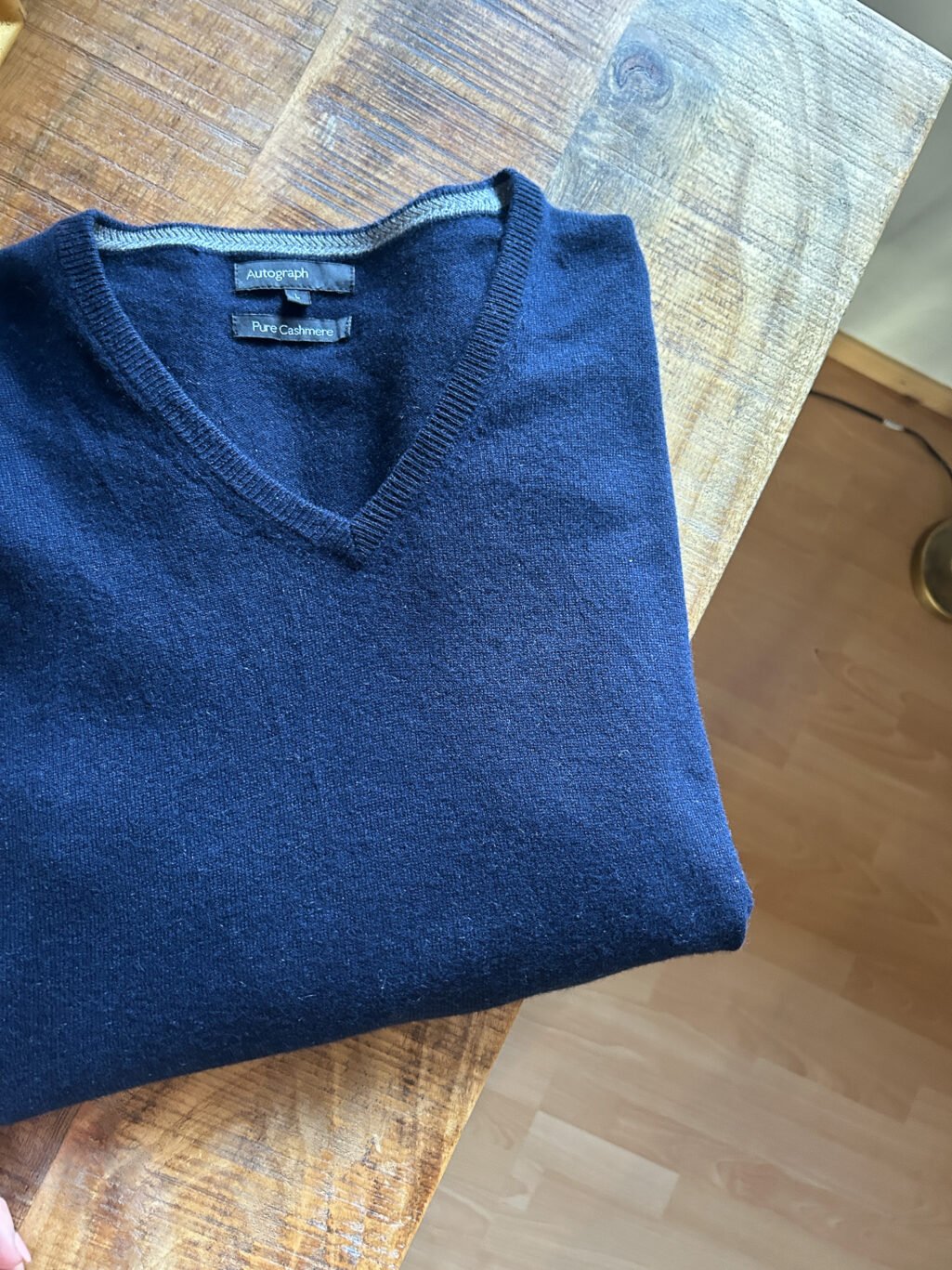 Blauer Autograph Cashmere Pullover mit V-Neck f&uuml;r Herren. Gefaltet auf Holztisch.