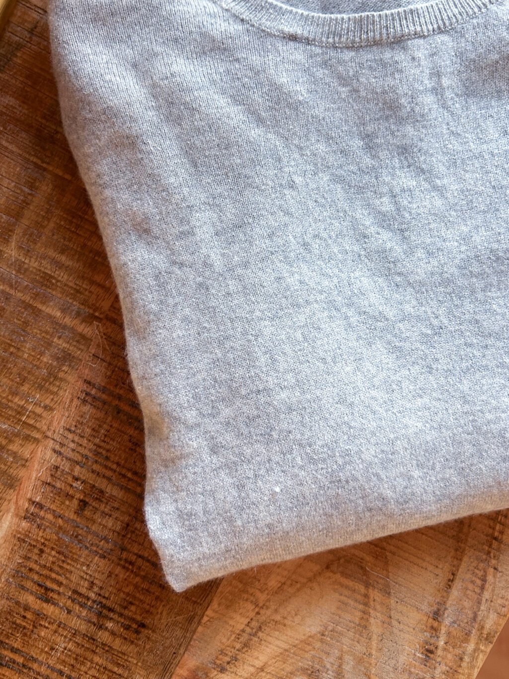 Tex Secondhand Cashmere Pullover in Grau, gefaltet auf Holztisch.